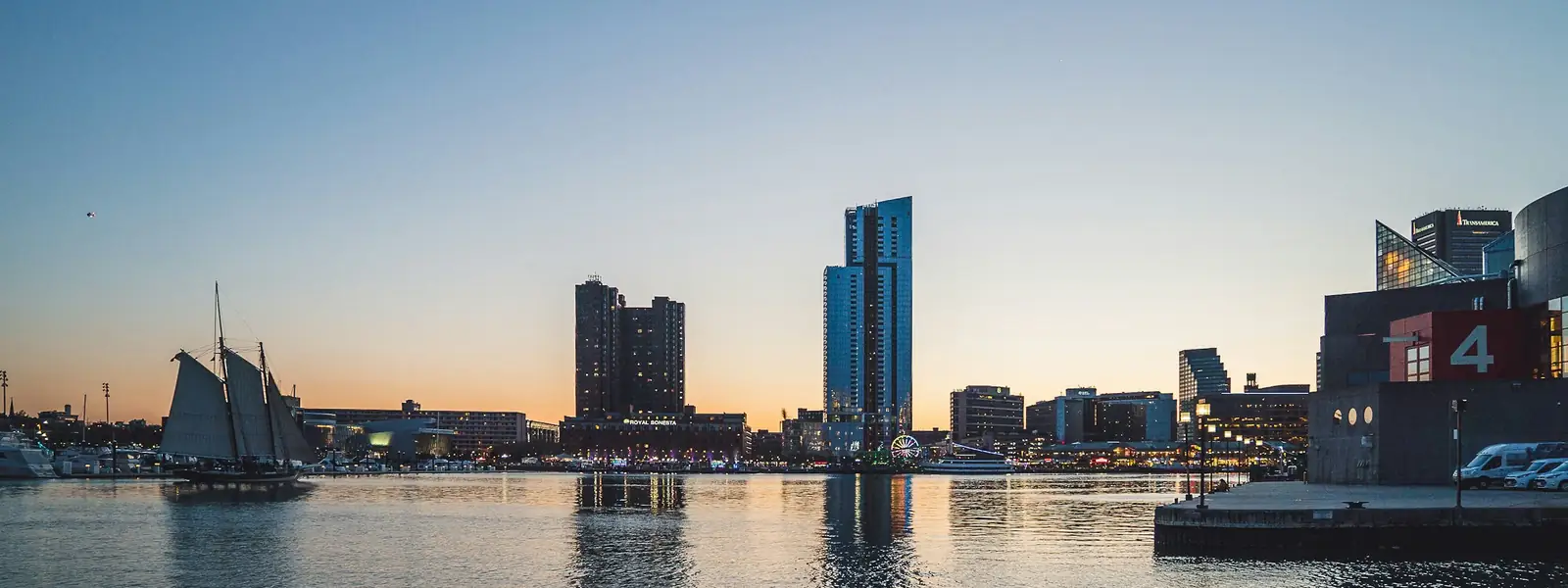 Baltimore's Inner Harbor at sunset, with a tall ship and the skyline
